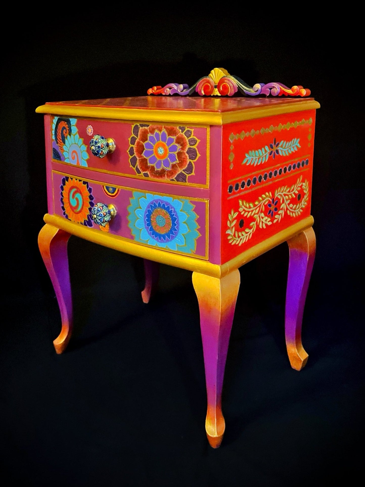 La cómoda parece un portal a una dimensión mítica: cada mandala — un mapa hacia el centro y cada color — un latido sin miedo que respira pasión, hojas y símbolos que arden sin consumir, y una figura oriental que toca la música del alma encendida.